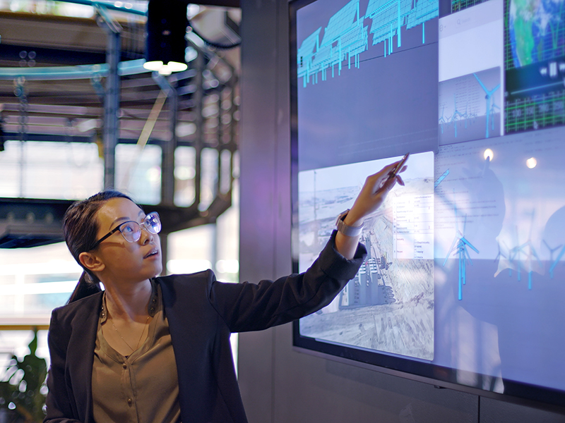 Woman pointing to graphs and charts on electronic touch board