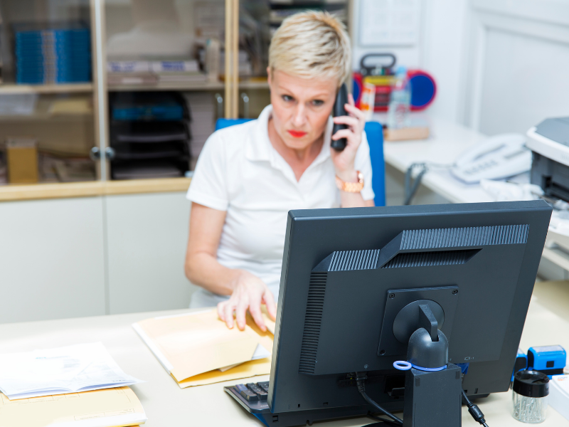 An irate woman sits behind a desk on the phone
