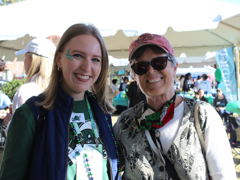 Professor and young woman pose together dress in Tulane swag