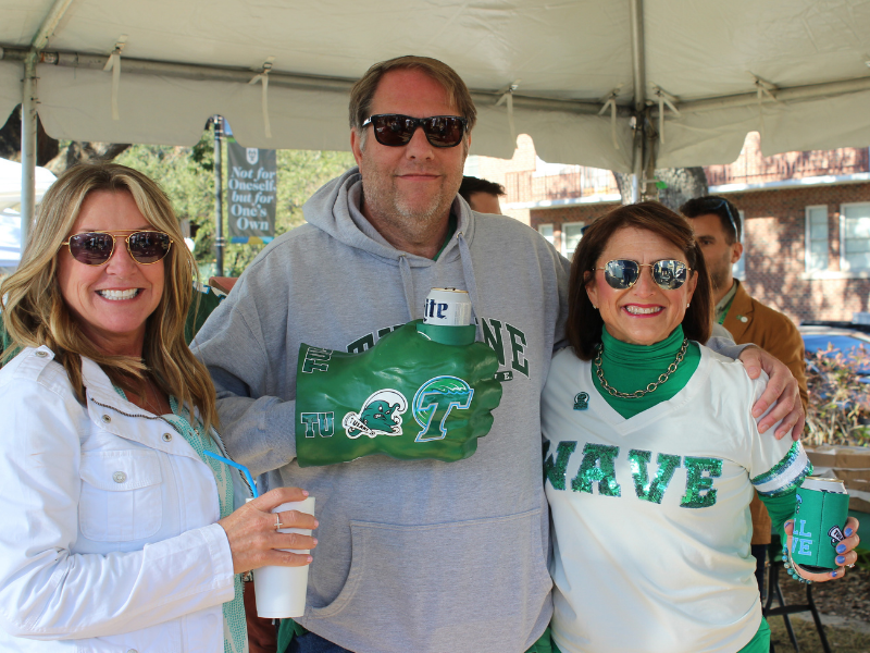 Three football fans pose in Tulane Swag at homecoming