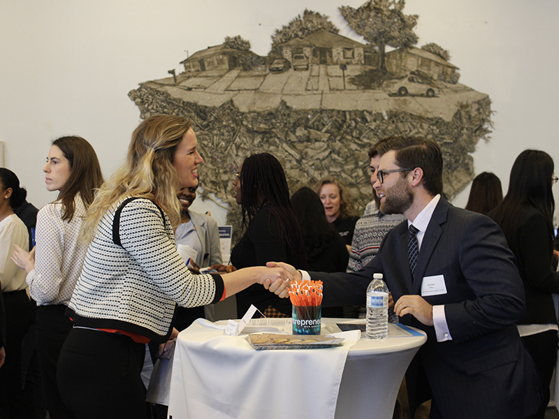People shaking hands over a table at a networking event