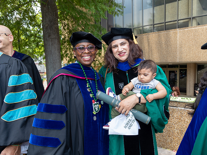 doctoral student in regalia with her baby