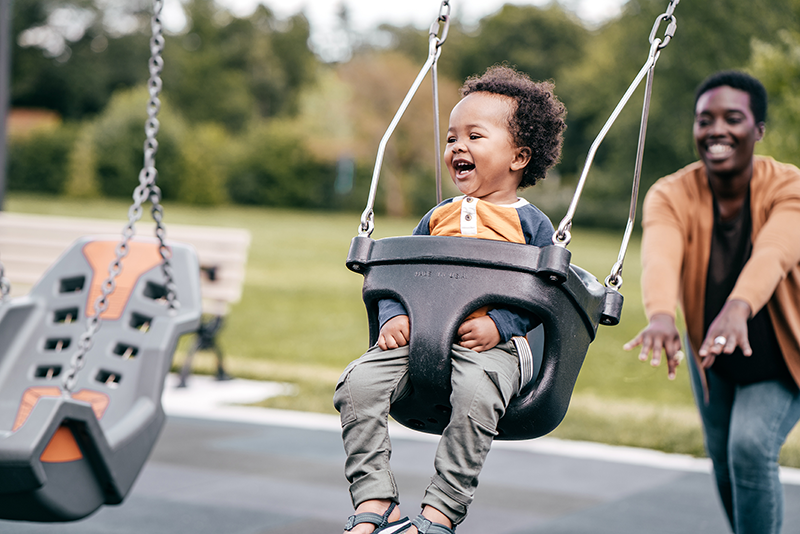Small child on a swing being pushed by mom