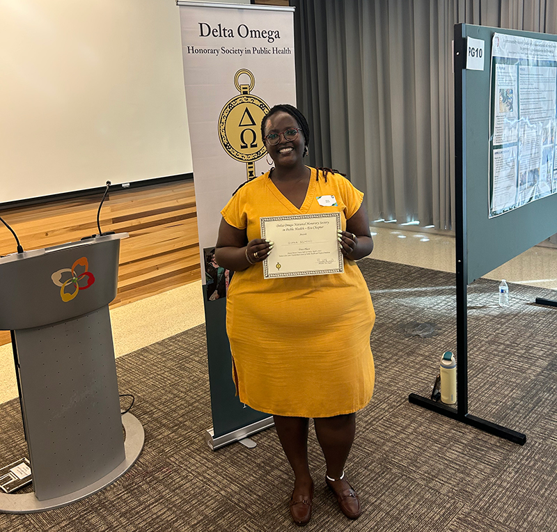 Gloria Igihozo with a certificate for first place in the Delta Omega poster competition