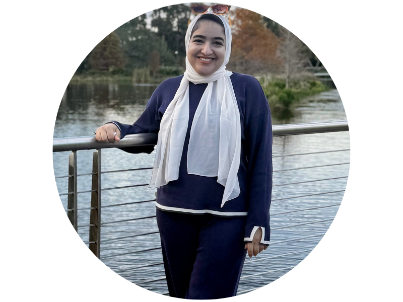 Wafaa Elwakli standing near a body of water, next to a railing, smiling at the camera
