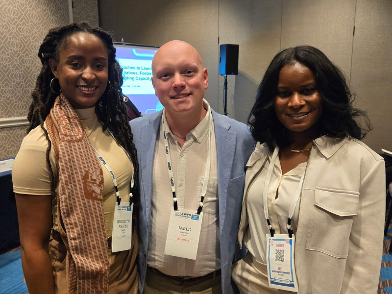 Three people smiling together at a conference with name badges.