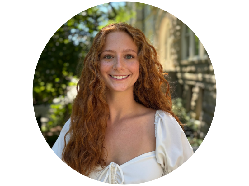 Ava Christiansen , with long red curly hair, wearing a white blouse and smiling at camera, standing outside Gibson Hall on Tulane University's uptown campus
