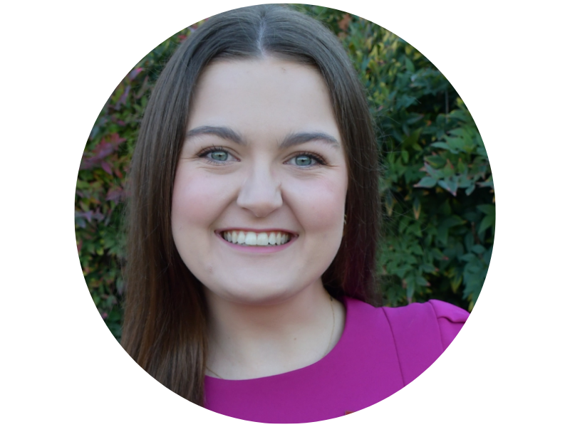 Katie Roman smiling, a young woman with brown hair, blue eyes, and a bright pink top.