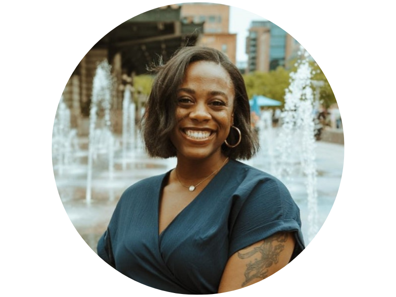 Madison Jones, smiling, wearing a teal dress and standing  in front of a series of small fountains