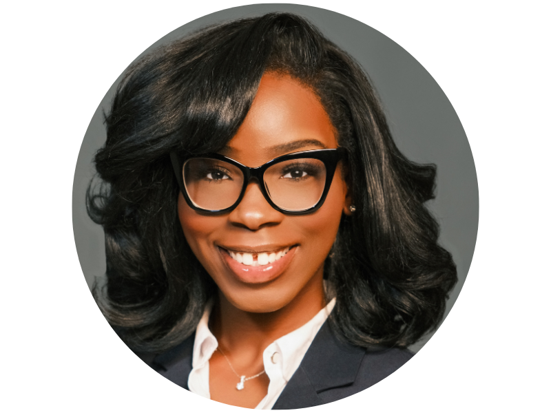 Marvellous Wells headshot, wearing glasses and a grey suit, smiling