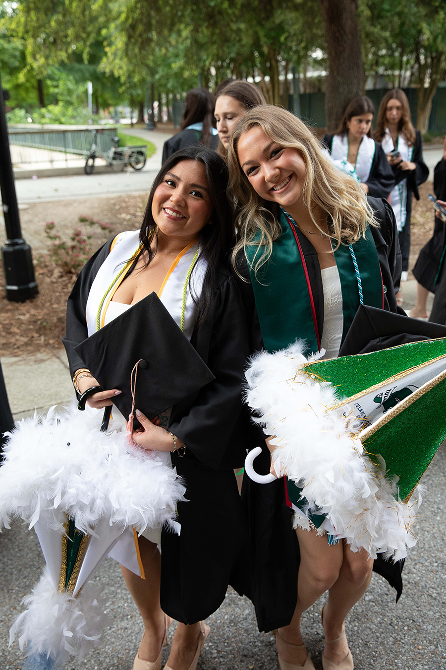 Two women graduates holding their decorated parasols