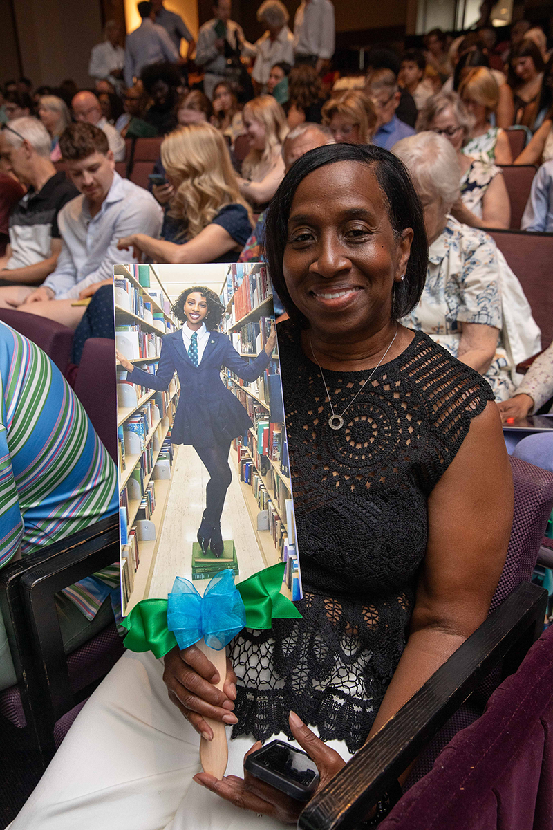 A proud parent holding a photo of her graduating daughter