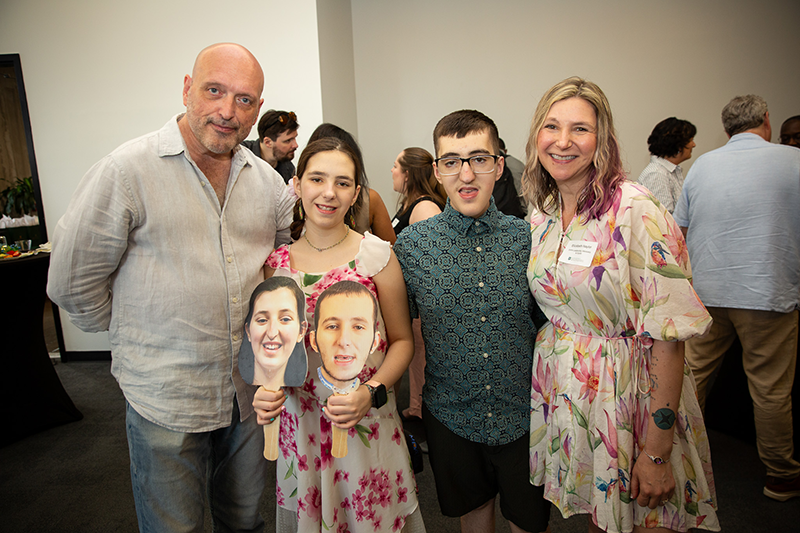 Elizabeth Naylor and her family with faces on sticks of her two deceased children