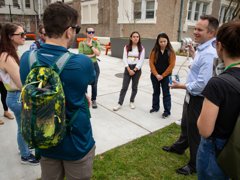 Rustin Reed addresses a group of students gathered outdoors on Tulane's campus.
