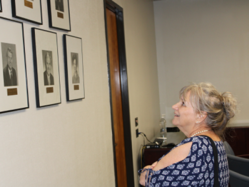 Dean Banta’s daughter, Wendy Banta Parham, studies the collection of dean portrait photos.