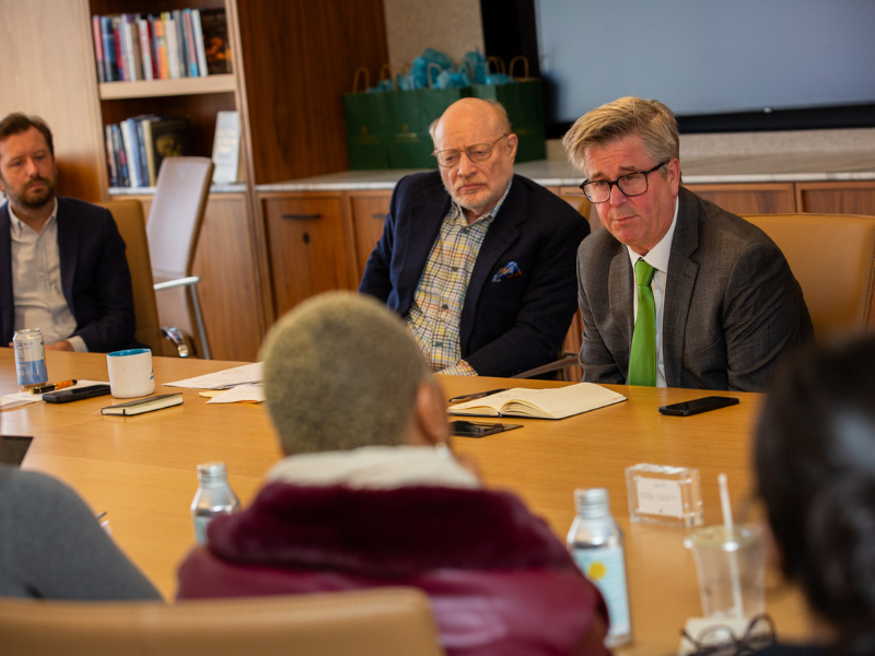 Business meeting: two men intently focused, one with a green tie.