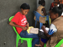 Child administering an injection to himself and healthcare worker looking on