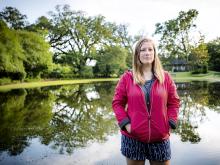 Laura Scott stands in front of a scenic body of water 