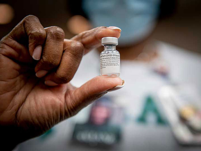 Person holding vial that says COVID-19 Vaccine